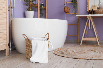 Poster - Basket with towel near modern bathtub in stylish bathroom interior