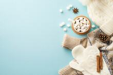Top View Photo Of Knitted Hat Mittens Sweater Mug Of Hot Drinking With Marshmallow On Rattan Serving Mat Pine Cone Anise Cinnamon Sticks On Isolated Light Blue Background With Copyspace