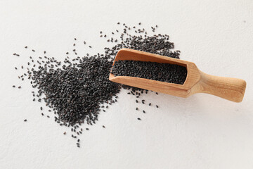 Canvas Print - Wooden scoop with black sesame seeds on light background