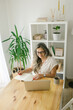 © STUDIO TAURUS - Woman sitting, taking notes from online class at home