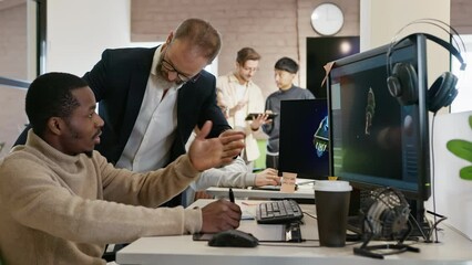 The CEO of the company studio developers of games and applications discusses with the artist a 3D model on a computer against the background of other employees of the company.