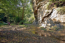 A Couple Pauses Near A Sheer Wall Of Sandstone That Rises Above Clifty Creek In Pine Hills Nature Preserve, Indiana.