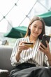 © StockPhotoRepublic - Close up photo of young asian beautiful female lady making a payment for an online shopping purchase via her smart phone easily and successful while sitting in a cafe