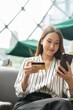 © StockPhotoRepublic - Close up photo of young asian beautiful female lady making a payment for an online shopping purchase via her smart phone easily and successful while sitting in a cafe