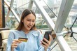 © StockPhotoRepublic - Young asian beautiful female lady making a payment for an online shopping purchase via her smart phone easily and successful while sitting in a cafe