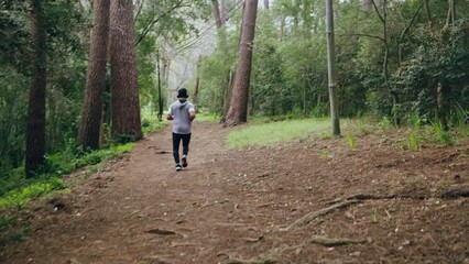 Wall Mural - Running, fitness and exercise with a sports man listening to music on headphones and training in the forest or woods. Workout, wellness and health with a male athlete or runner out on a run for sport