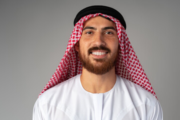 Wall Mural - Portrait of smiling young Arab man on gray background