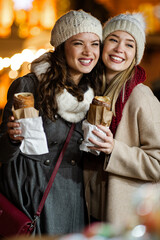Wall Mural - festive christmas fair concept. happy women having fun and shopping, enjoying on christmas market.
