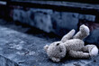 Dirty teddy bear toy lies outdoors on the road as symbol of children's loneliness, pain, loss childhood and future. Copy space for text