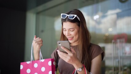 Wall Mural - Happiness Beautiful woman enjoy shopping with smartphone , shopping bag at fashion mall. Trendy female shopping at clothes store. Smiling Woman enjoying lifestyle fashion. Shopping mall concept.