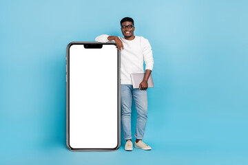 Wall Mural - Full body photo of smiling skilled freelancer lean on big smartphone display isolated on blue color background