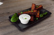 Tasty, spicy black bread croutons with garlic sauce, salt and basil on black plate on wooden table in cafe. Junk food