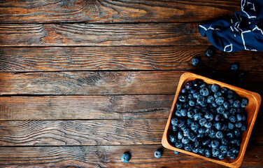 Canvas Print - Freshly picked blueberries in wooden bowl. Juicy and fresh blueberries with green leaves on rustic table. Bilberry on wooden Background. Blueberry antioxidant. Concept for healthy eating and nutrition