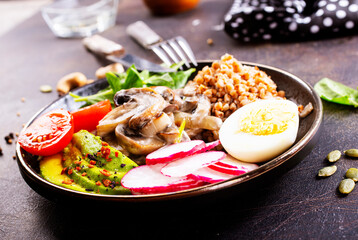 Wall Mural - Cooked Buckwheat with avocado and mushrooms served in a bawl for breakfast. Gluten free meal.