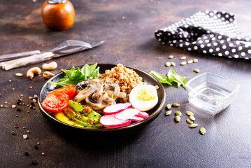 Wall Mural - Cooked Buckwheat with avocado and mushrooms served in a bawl for breakfast. Gluten free meal.