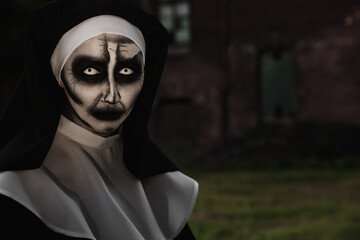 Wall Mural - Portrait of scary devilish nun outdoors, space for text. Halloween party look