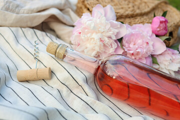 Sticker - Bottle of rose wine and beautiful peonies on light blanket, closeup