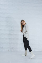 Wall Mural - Photo of a young woman in white boots and casual clothes. New collection of women's winter shoes made of genuine leather.