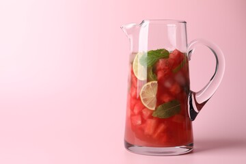 Wall Mural - Tasty summer watermelon drink with lime in glass jug on pink background. Space for text