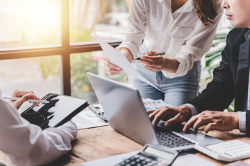 Wall Mural - Young colleagues discussing business and price chart analyzes business people on the table great in modern coworking office teamwork concept. Calculate personal tax for customers