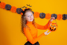 Teenage Girl In A Witch Costume On A Yellow Background, Holding A Confent Pumpkin Eating Marmalade Worms Halloween Party