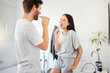 Love, morning and couple in bathroom brushing teeth together doing daily routine, happy and smile. Man and woman with good dental health, mouth care and cleaning teeth with toothbrush and toothpaste