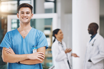 Wall Mural - Portrait of a male nurse with his team in the background in the hospital. Happy, smiling and confident nurse with doctors in medicine, health and medical care. Medical team, healthcare and nursing