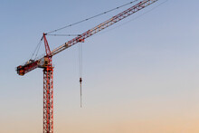 Red Crane Against Clear Sunset Sky. Construction Industry. Copy Space For Text