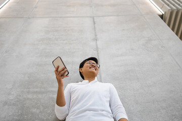 Wall Mural - Smiling young man using mobile phone
