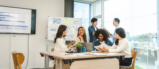 Young and successful mixed race, asian business people working on project together, sitting at table in boardroom.