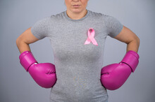A Faceless Woman In Pink Boxing Gloves With A Pink Ribbon Holds Her Hands At Her Hips. Fight Against Breast Cancer. 