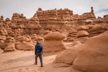 Man Hiking Among Red Rock Formations In Goblin Valley State Park In Utah.