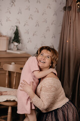 Portrait of a smiling woman with short dark hair in a dress hugging her daughter. A little girl in a pink dress with Down Syndrome hugs her mother. The concept of love and care.