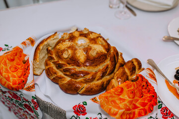 Wall Mural - A beautiful Ukrainian loaf broken into pieces stands on a table with an embroidered towel. Food photography.