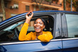 © mimagephotos - Happy black woman sitting in her new car and showing keys