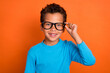 Close up photo of positive cute boy hand touch eyeglasses like new accessory wear stylish blue jumper isolated on orange color background