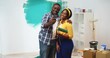 © ihorvsn - POV of happy joyful young cute African American couple speaking on video chat with friends or designer in new home, house renovation man and woman videochatting through web cam online close up concept