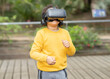 © PintoArt - African American boy playing with virtual reality glasses outdoors.