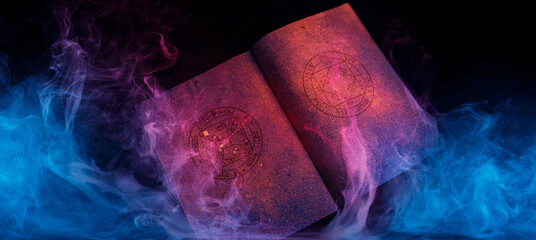 A magic book in ultraviolet light on dark background. Mysterious composition. Fortune teller, mind power, prediction, halloween concept. Wide angle horizontal wallpaper or web banner.