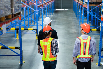 Group of warehouse workers walking and checking on stock before shipping delivery in the factory. Staff with client visiting at distribution center. Logistic business career.