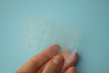 acne treatment anti-cellulite patch for acne in a woman's hand on a blue background.