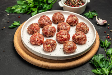 Wall Mural - raw meatballs on wooden board, minced pork meat with spices on a dark background. banner, menu, recipe place for text, top view