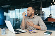 © Liubomir - Sick office worker with asthma having trouble breathing, man using inhaler to relieve breathing, hispanic man working inside modern office building, mixed race man with laptop