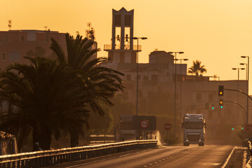 Wall Mural - Truck leaving a town for a crossing with traffic lights, with the lights of dawn.