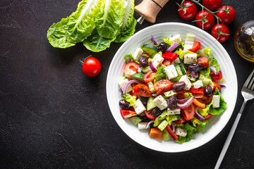 Wall Mural - Greek salad. Vegetable salad with tomato, cucumber, feta cheese and olive oil. Top view on black stone table.