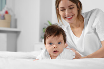 Poster - Cute little baby and mother on cosy bed in room, space for text