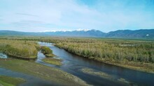 Aerial Panoramic Landscape Of Snow Capped Sayan Mountains, Valley And River On A Bright Sunny Day. Picturesque Scenery Of Siberian Nature