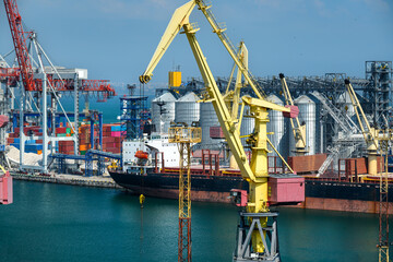 Wall Mural - industrial seaport infrastructure, sea, cranes and dry cargo ship, grain silo and bulk carrier vessel, concept of sea cargo transportation