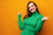 © fotofabrika - Portrait of an excited young woman celebrating success with raised arms against yellow background