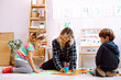 © Татьяна Волкова - Kind teacher conduct lesson for little children while sitting on floor in playing room. Kids play with toys and draw picture with colored pencils in kindergarten. Lesson, preschool, daycare